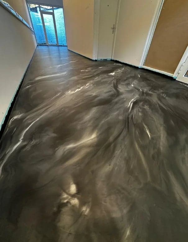 Long couloir en résine métallisée gris et blanc, lumière d'une porte vitrée