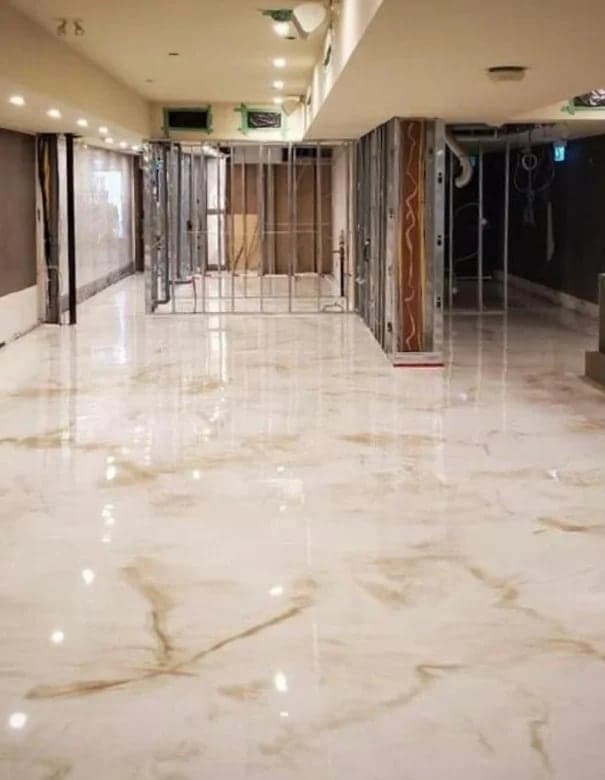 Grand hall en résine marbrée blanche aux veines dorées, très brillante