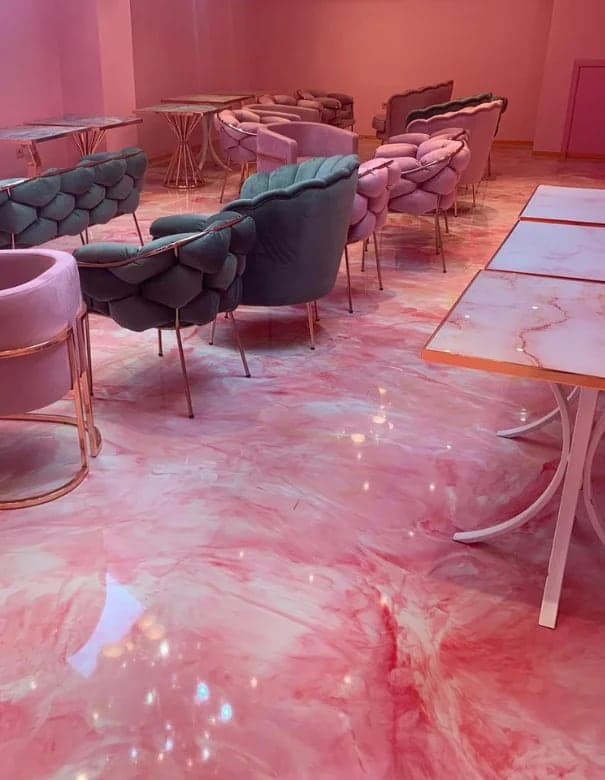 Salon de thé aux fauteuils roses posé sur un sol en résine marbrée rose et blanche